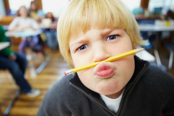Funny young school student balancing a pencil on his nose